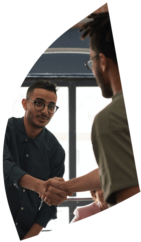 ein Personallvermittler und ein Bewerber die sich die Hände reichen in einem Büro, interkulturelle Kontex